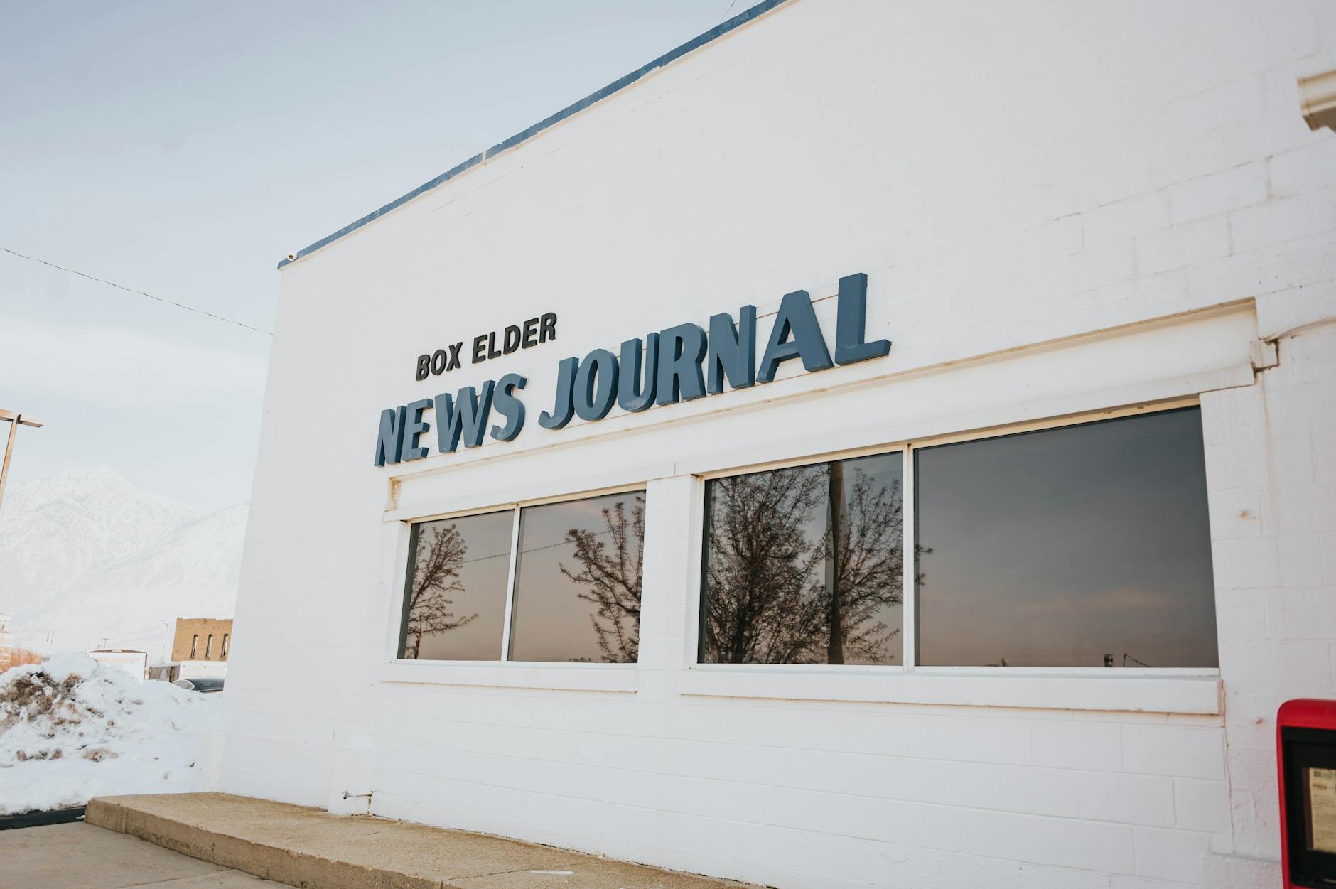Exterior view of Box Elder News Journal with snowy surroundings and reflective windows.